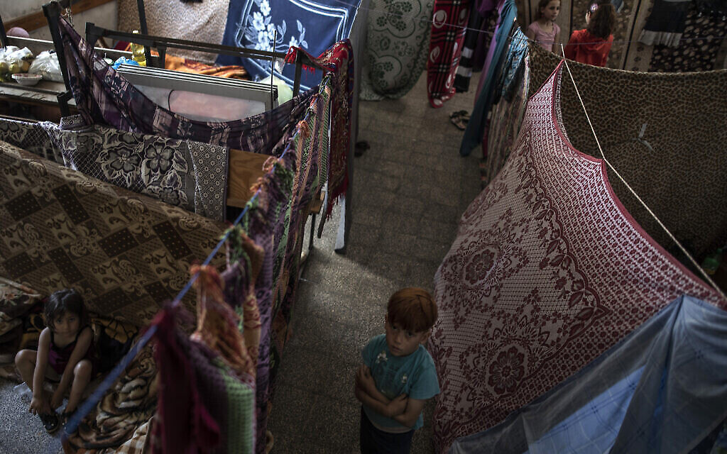 Des Palestiniens s'abritent dans une école gérée par l'ONU après avoir fui les frappes de missiles israéliens en réponse aux tirs de roquettes dans la banlieue de la ville de Gaza, le 19 mai 2021 (Crédit : AP Photo/Khalil Hamra).