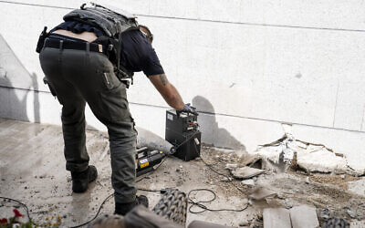Un technicien inspecte un missile non explosé tiré depuis la bande de Gaza qui a atterri au dernier étage d'un immeuble résidentiel à Ashkelon, le 20 mai 2021. (Crédit : AP Photo/John Minchillo)