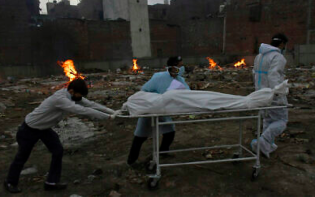 Le corps d'une victime du COVID-19 est emmené pour être incinéré dans un terrain qui a été converti en crématorium à New Delhi, en Inde, le 6 mai 2021 (Crédit : AP Photo / Ishant Chauhan)