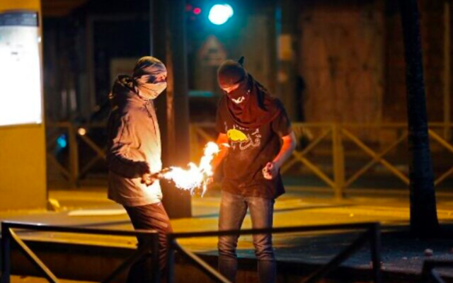 Photo d'illustration : Des émeutiers palestiniens allument un cocktail Molotov lors d'affrontements avec les forces israéliennes dans le quartier de Shuafat à Jérusalem-Est le 14 mai 2021 (Ahmad GHARABLI / AFP)