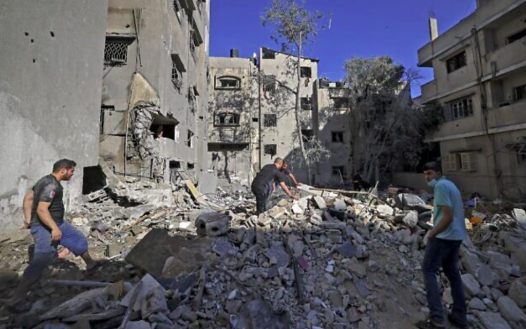 Des Palestiniens recherchent des biens à récupérer parmi les décombres d'un immeuble suite aux frappes aériennes israéliennes menées dans Gaza city après des pluies de roquettes du groupe terroriste palestinien du Hamas, à la tête de l'enclave, le 15 mai 2021 (Crédit : MAHMUD HAMS / AFP)