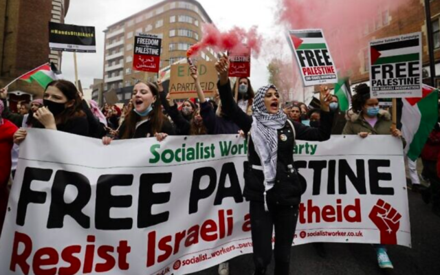 Des militants et partisans pro-palestiniens à Londres lancent des torches de fumée, agitent des drapeaux et brandissent des pancartes lors d'une manifestation contre Israël au milieu des combats entre l'État juif et les terroristes palestiniens à Gaza, le 15 mai 2021 (Crédit : Tolga Akmen / AFP)