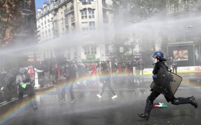 Un policier français court vers des manifestants pro-palestiniens qui manifestent à Paris malgré une interdiction des autorités françaises, le 15 mai 2021 (Geoffroy Van Der Hasselt / AFP)