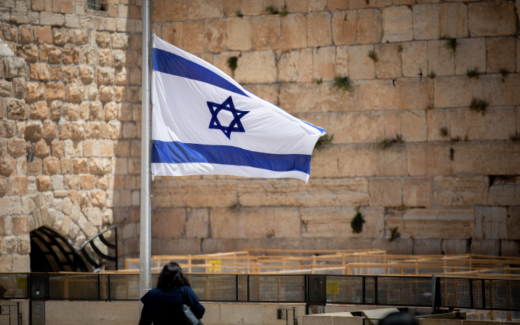 Les gens marchent à côté d'un drapeau israélien en l'honneur des victimes du mont Meron, victimes de la catastrophe, au mur Occidental dans la Vieille Ville de Jérusalem, le 2 mai 2021 (Crédit : Yonatan Sindel / Flash90)