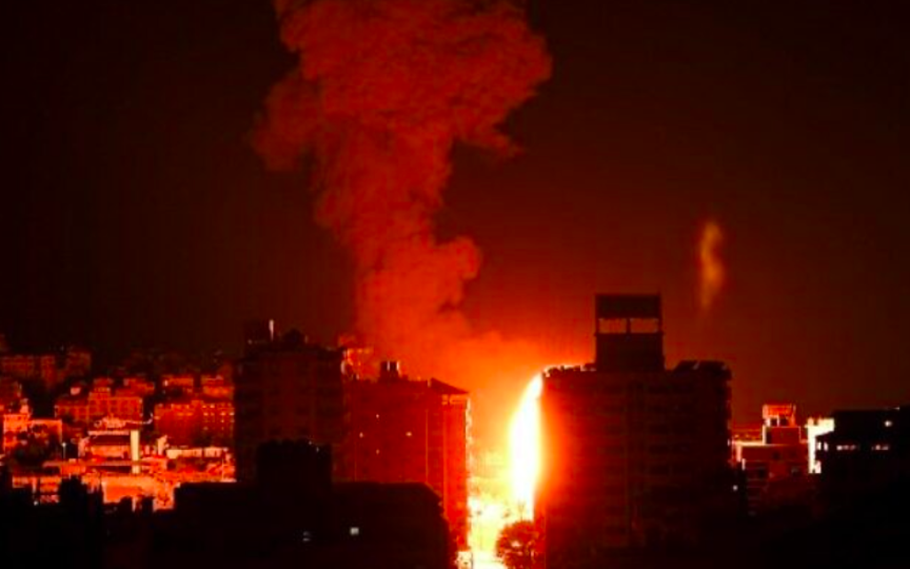 Le feu et la fumée s'élèvent au-dessus des bâtiments de la ville de Gaza alors que les avions de combat israéliens effectuent des frappes en représailles aux roquettes tirées par le Hamas, tôt le 17 mai 2021 (Crédit : MAHMUD HAMS / AFP)