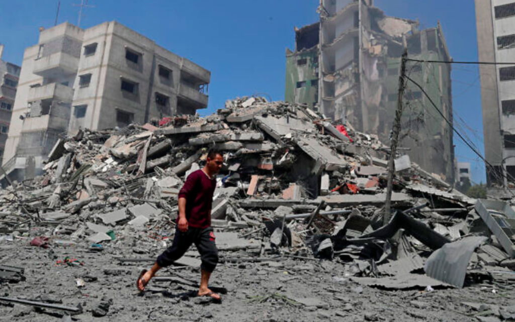 Un homme passe devant les décombres de l'immeuble résidentiel de Yazegi qui a été détruit par une frappe aérienne israélienne menée à Gaza City en représailles aux roquettes tirées par le Hamas, dimanche 16 mai 2021. (Crédit : AP Photo / Adel Hana)