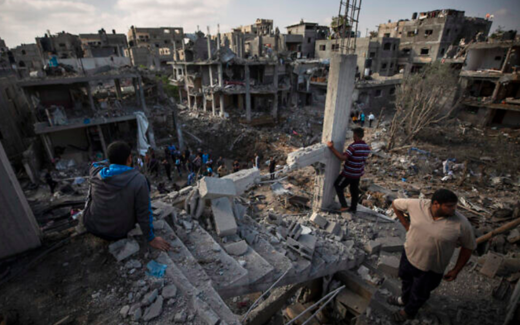 Des Palestiniens inspectent des bâtiments détruits à la suite de frappes aériennes israéliennes pendant la nuit à Beit Hanoun, dans le nord de la bande de Gaza, le 14 mai 2021 (Crédit : AP Photo / Khalil Hamra)