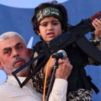 Le chef du Hamas, Yahya Sinwar, tient l'enfant d'un membre des Brigades Ezzedin  Al-Qassam, tué lors des récents combats avec Israël, le 24 mai 2021. (Crédit : Emmanuel Dunand/AFP)