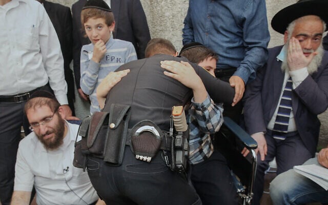 L'officier de police Rami Alwan étreint Shmuel Hayut, qu'il a sauvé à Meron. Le père Avigdor Hayut se trouve à gauche, dans leur maison à Bnei Brak, le 3 mai 2021. (Flash90) L'officier de police Rami Alwan étreint Shmuel Hayut, qu'il a sauvé à Meron. Le père Avigdor Hayut se trouve à gauche, dans leur maison à Bnei Brak, le 3 mai 2021. (Flash90)