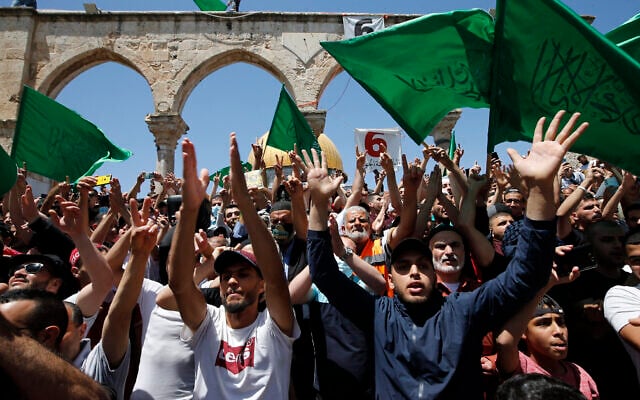 Des Palestiniens brandissent des drapeaux du groupe terroriste du Hamas après les prières de l'après-midi au cours du dernier vendredi du mois du Ramadan, sur le mont du Temple, dans la Vieille Ville de Jérusalem, le 7 mai 2021. (Crédit : Jamal Awad/Flash90) Des Palestiniens brandissent des drapeaux du groupe terroriste du Hamas après les prières de l'après-midi au cours du dernier vendredi du mois du Ramadan, sur le mont du Temple, dans la Vieille Ville de Jérusalem, le 7 mai 2021. (Crédit : Jamal Awad/Flash90)