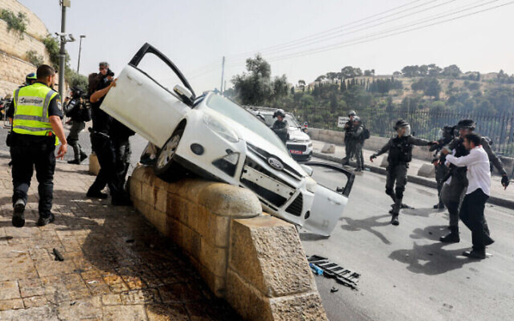 Les forces de sécurité israéliennes devant une voiture qui a été la cible de jets de pierres à l'extérieur de la vieille ville de Jérusalem, le 10 mai 2021. (Crédit : Olivier Fitoussi/Flash90)