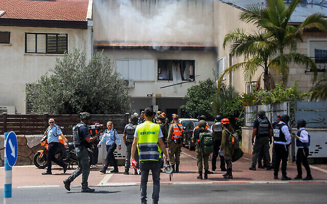 Les forces de sécurité israéliennes devant une maison d'Ashdod touchée par une roquette tirée depuis la bande de Gaza, le 11 mai 2021. (Crédit : Flash90) Les forces de sécurité israéliennes devant une maison d'Ashdod touchée par une roquette tirée depuis la bande de Gaza, le 11 mai 2021. (Crédit : Flash90)