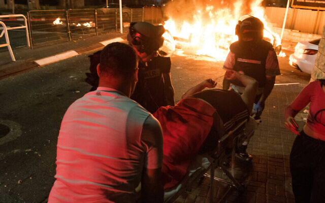 Des secouristes évacuent un homme blessé lors d'affrontements entre Arabes et Juifs à Acre, dans le nord d'Israël, le 12 mai 2021. (Crédit : Roni Ofer/Flash90) Des secouristes évacuent un homme blessé lors d'affrontements entre Arabes et Juifs à Acre, dans le nord d'Israël, le 12 mai 2021. (Crédit : Roni Ofer/Flash90)