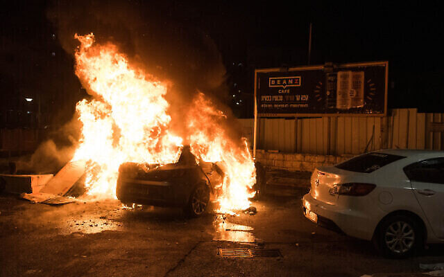 Une voiture en feu suite à des affrontements entre Arabes et Juifs à Akko, dans le nord d'Israël, le 12 mai 2021. (Crédit : Roni Ofer/Flash90)