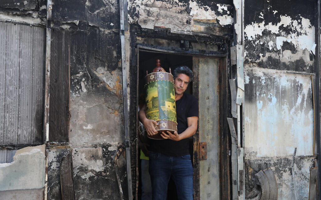 Des Israéliens extraient des rouleaux de Torah d'une synagogue incendiée à Lod après une émeute d'Arabes israéliens, le 12 mai 2021. (Crédit : Yonatan Sindel/Flash90)