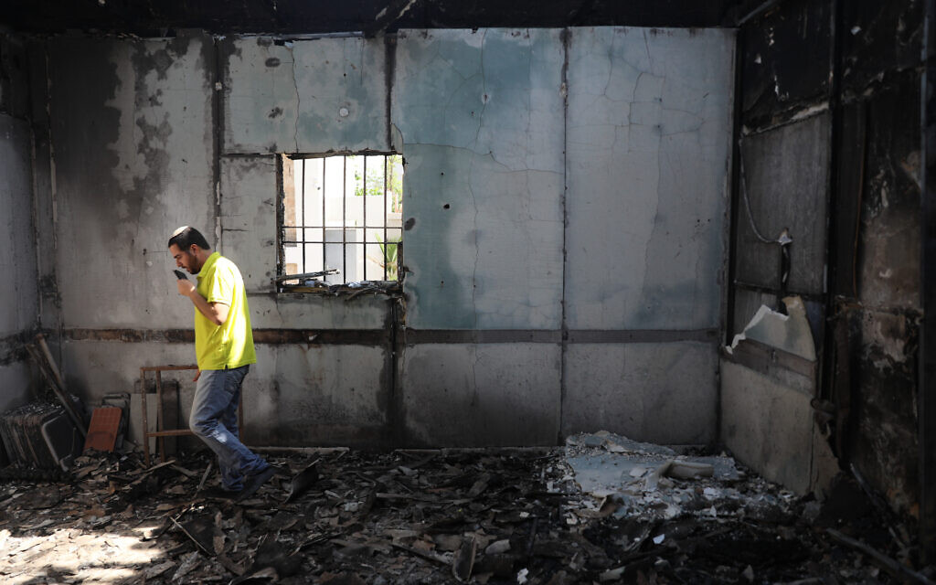 Des Israéliens extraient des rouleaux de Torah d'une synagogue incendiée à Lod après une émeute d'Arabes israéliens, le 12 mai 2021. (Crédit : Yonatan Sindel/Flash90)