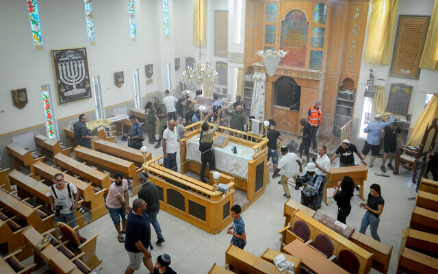 Des fidèles nettoient l'intérieur d'une synagogue endommagée suite à un tir de roquette de Gaza à Ashkelon, le 16 mai 2021. (Crédit : Avi Roccah/Flash90)