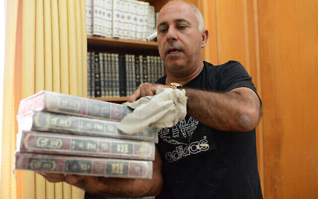Des fidèles nettoient l'intérieur d'une synagogue endommagée suite à un tir de roquette de Gaza à Ashkelon, le 16 mai 2021. (Crédit : Tomer Neuberg/Flash90)