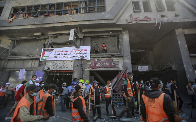 Des bénévoles palestiniens nettoient les décombres dans une rue de Gaza City après des frappes israéliennes pendant l'Opération Gardien des murs, le 23 mai 2021. (Crédit : Atia Mohammed/Flash90) Des bénévoles palestiniens nettoient les décombres dans une rue de Gaza City après des frappes israéliennes pendant l'Opération Gardien des murs, le 23 mai 2021. (Crédit : Atia Mohammed/Flash90)