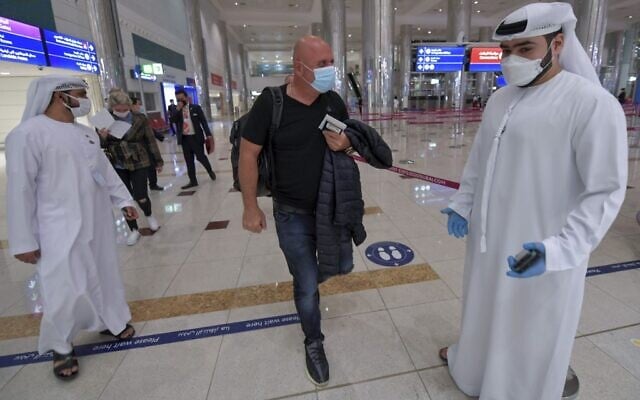 Un Israélien passant devant le personnel émirati après le contrôle des passeports à son arrivée de Tel Aviv à l'aéroport de Dubaï, aux Émirats arabes unis, le 26 novembre 2020, lors du premier vol commercial régulier opéré par la compagnie aérienne à flydubai, suite à la normalisation des liens entre les EAU et Israël. (Crédit : Karim Sahib/AFP)