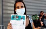 Une participante montre son passeport vert lors d'un concert à Tel Aviv le 5 mars 2021, qui était exclusivement réservé aux personnes le possédant. (Crédit : Photo de JACK GUEZ / AFP)