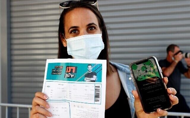 Une participante montre son passeport vert lors d'un concert à Tel Aviv le 5 mars 2021, qui était exclusivement réservé aux personnes le possédant. (Crédit : Photo de JACK GUEZ / AFP) Une participante montre son passeport vert lors d'un concert à Tel Aviv le 5 mars 2021, qui était exclusivement réservé aux personnes le possédant. (Crédit : Photo de JACK GUEZ / AFP)