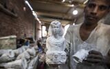 Un artisan manipule une réplique moulée d'une figurine de buste de l'ancienne Égypte dans un atelier du quartier de Nazlet el-Semman, près de la nécropole des pyramides de Gizeh, dans la ville jumelle de la capitale égyptienne, Gizeh, le 6 juin 2021. (Crédit : Khaled DESOUKI / AFP)