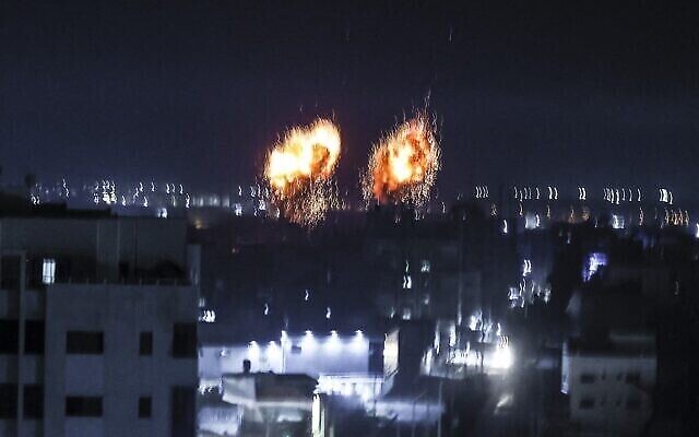 Des explosions illuminent le ciel nocturne au-dessus des bâtiments de la ville de Gaza, alors que les forces israéliennes bombardent l'enclave palestinienne, tôt le 16 juin 2021. (Crédit