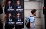 Un passant devant des pancartes collées par des membres du comité de soutien à Eric Zemmour dans une rue de Paris, le 28 juin 2021. (Crédit : Olivier MORIN / AFP)