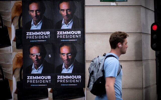Un passant devant des pancartes collées par des membres du comité de soutien à Eric Zemmour dans une rue de Paris, le 28 juin 2021. (Crédit : Olivier MORIN / AFP)