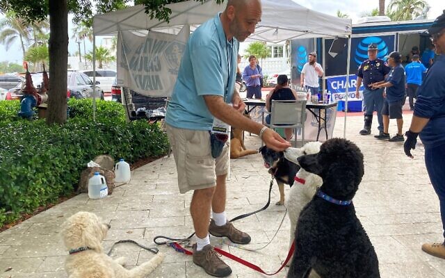 Jay Harris, bénévole de United Cajun Navy, nourrit les chiens qu'il a amenés pour la thérapie à Surfside, en Floride, le 28 juin 2021. (Crédit : Chris STEIN / AFP) Jay Harris, bénévole de United Cajun Navy, nourrit les chiens qu'il a amenés pour la thérapie à Surfside, en Floride, le 28 juin 2021. (Crédit : Chris STEIN / AFP)