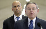 Le sénateur américain Cory Booker, en arrière plan, regarde le sénateur Bob Menendez prendre la parole lors d'une conférence de presse à l'aéroport international Newark Liberty, le 8 janvier 2019, à Newark, N.J. (Crédit : AP Photo/Julio Cortez)