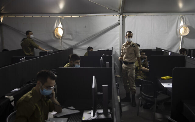 Les soldats israéliens s'entretiennent avec des personnes touchées par le coronavirus pour identifier ceux avec qui elles ont été en contact au siège du Commandement intérieur, à Ramle, le 25 août 2020. (Crédit : AP Photo/Sebastian Scheiner)
