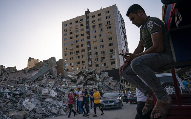 Des personnes se rassemblent pour voir les décombres de l'immeuble al-Jalaa dans la ville de Gaza, vendredi 21 mai 2021. L'immeuble a abrité le bureau de l'Associated Press dans la ville de Gaza pendant 15 ans. (Crédit : AP/John Minchillo) Des personnes se rassemblent pour voir les décombres de l'immeuble al-Jalaa dans la ville de Gaza, vendredi 21 mai 2021. L'immeuble a abrité le bureau de l'Associated Press dans la ville de Gaza pendant 15 ans. (Crédit : AP/John Minchillo)