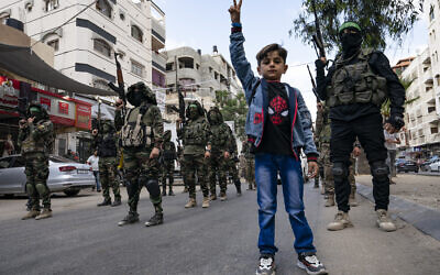 Des enfants devant les militants du Hamas lors d'un défilé en hommage à Bassem Issa, commandant du groupe terroriste qui a été tué par l'armée israélienne avant le cessez-le-feu qui a mis un terme au conflit de onze jours entre Israël et les groupes terroristes de la bande de Gaza, le 22 mai 2021. (Crédit : AP Photo/John Minchillo)