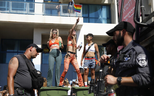 Des fêtards dansent sur des poubelles alors que la police assure la sécurité à la Marche des Fiertés annuelle à Tel Aviv, le 25 juin 2021. (Crédit : AP Photo/Ariel Schalit) Des fêtards dansent sur des poubelles alors que la police assure la sécurité à la Marche des Fiertés annuelle à Tel Aviv, le 25 juin 2021. (Crédit : AP Photo/Ariel Schalit)