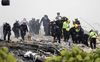 Des membres de l'équipe de recherche et de sauvetage urbain de Floride du Sud recherchent d'éventuels survivants dans l'immeuble à condos Champlain Towers South de 12 étages partiellement effondré, le 25 juin 2021 à Surfside, en Floride. (Crédits:Joe Raedle/Getty Images)