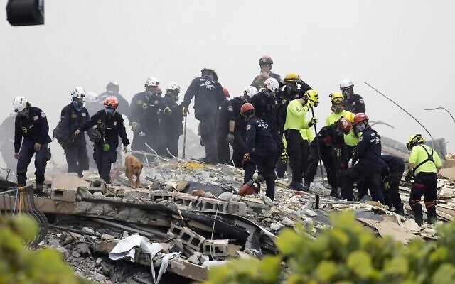 Des membres de l'équipe de recherche et de sauvetage urbain de Floride du Sud recherchent d'éventuels survivants dans l'immeuble à condos Champlain Towers South de 12 étages partiellement effondré, le 25 juin 2021 à Surfside, en Floride. (Crédits:Joe Raedle/Getty Images)
