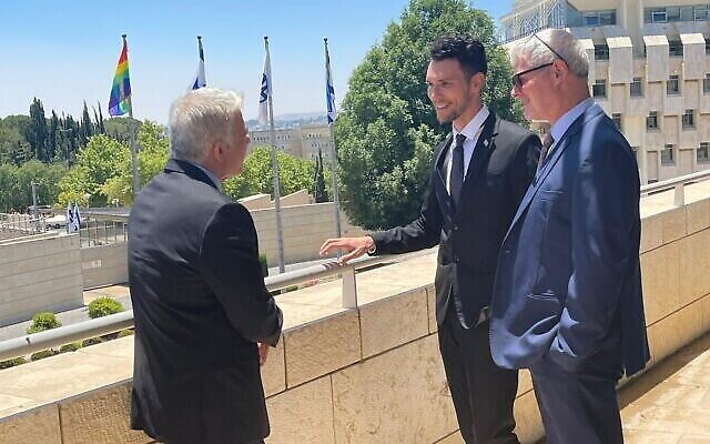 Le ministre des Affaires étrangères Yair Lapid, le vice-ministre des Affaires étrangères Idan Roll et le directeur général du ministère des Affaires étrangères Alon Ushpiz, à côté du drapeau LGBT installé le 21 juin 2021. (Crédit : Ministère des affaires étrangères)