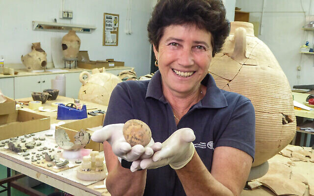 Alla Nagorsky, archéologue de l'Autorité israélienne des antiquités, avec l'œuf vieux de 1000 ans qui a été retrouvé à Yavne.  (Crédit : Yoli Schwartz/Israel Antiquities Authority)