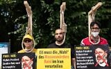 Des manifestants posent avec des potences factices alors qu'ils participent à une manifestation appelée par le Conseil national de la résistance iranienne (CNRI) contre le régime iranien, devant la porte de Brandebourg à Berlin, le 10 juillet 2021. (Crédit : Paul Zinken/AFP)