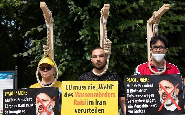 Des manifestants posent avec des potences factices alors qu'ils participent à une manifestation appelée par le Conseil national de la résistance iranienne (CNRI) contre le régime iranien, devant la porte de Brandebourg à Berlin, le 10 juillet 2021. (Crédit : Paul Zinken/AFP) Des manifestants posent avec des potences factices alors qu'ils participent à une manifestation appelée par le Conseil national de la résistance iranienne (CNRI) contre le régime iranien, devant la porte de Brandebourg à Berlin, le 10 juillet 2021. (Crédit : Paul Zinken/AFP)