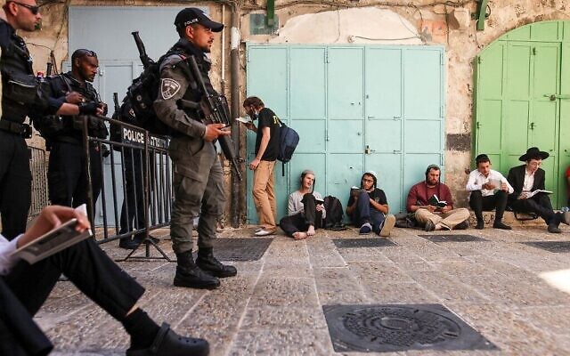 Des hommes juifs à l'extérieur de l'enceinte de la mosquée Al-Aqsa à Jérusalem, alors que les forces de sécurité israéliennes montent la garde lors du jeûne annuel de Tisha BeAv (9 du mois d’Av), le 18 juillet 2021. (Crédit : AHMAD GHARABLI / AFP) Des hommes juifs à l'extérieur de l'enceinte de la mosquée Al-Aqsa à Jérusalem, alors que les forces de sécurité israéliennes montent la garde lors du jeûne annuel de Tisha BeAv (9 du mois d’Av), le 18 juillet 2021. (Crédit : AHMAD GHARABLI / AFP)