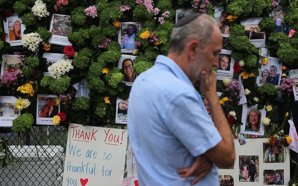 Un homme passe devant un mémorial où figurent les photos de certains des disparus de l'immeuble de 12 étages Champlain Towers South, à Surfside, en Floride, qui s'est partiellement effondré, le 28 juin 2021. (Crédit : Joe Raedle/Getty Images/AFP)