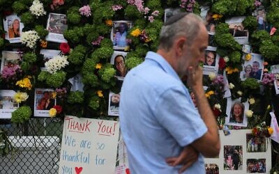 Un homme passe devant un mémorial où figurent les photos de certains des disparus de l'immeuble de 12 étages Champlain Towers South, à Surfside, en Floride, qui s'est partiellement effondré, le 28 juin 2021. (Crédit : Joe Raedle/Getty Images/AFP)