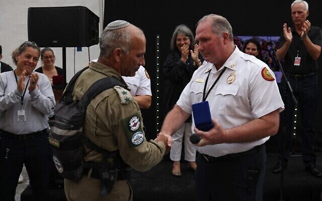 SURFSIDE, FLORIDA - JULY 10: Le chef des sapeurs-pompiers du comté de Miami Dade, Alan Cominsky, remet une médaille à Golan Vach, commandant de l'unité de secours de l'armée israélienne envoyée en Floride suite à la catastrophe de Surfside, lors d'une cérémonie en date du 10 juillet 2021. (Crédit :  Anna Moneymaker / GETTY IMAGES NORTH AMERICA / Getty Images via AFP)