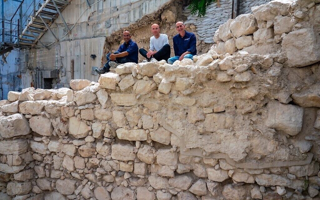 Les directeurs des fouilles assis sur la section exposée du mur de protection de l'époque du Premier Temple dans le périmètre oriental de Jérusalem. (Crédit : Yaniv Berman/ Autorité israélienne des antiquités)