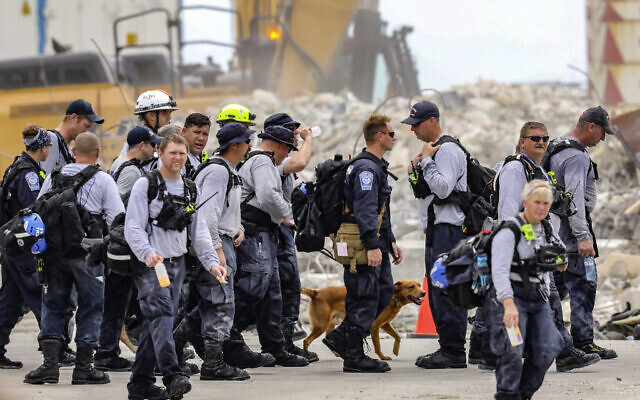 Des membres d'une équipe de recherche et de sauvetage partent après avoir travaillé sur le s ruines de l'immeuble Champlain Towers South, le 7 juillet 2021. (Crédit : Al Diaz/Miami Herald via AP) Des membres d'une équipe de recherche et de sauvetage partent après avoir travaillé sur le s ruines de l'immeuble Champlain Towers South, le 7 juillet 2021. (Crédit : Al Diaz/Miami Herald via AP)