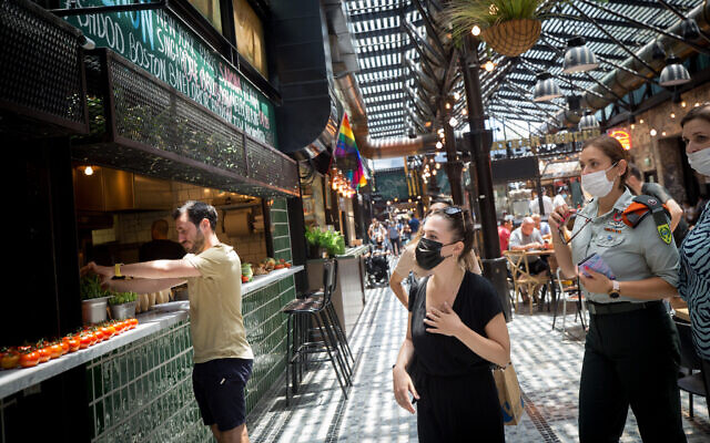 Des gens portent un masque de protection au marché Sanora de Tel Aviv, le 13 juillet 2021. (Crédit : Miriam Alster/FLASH90) Des gens portent un masque de protection au marché Sanora de Tel Aviv, le 13 juillet 2021. (Crédit : Miriam Alster/FLASH90)