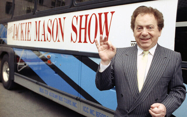 L'acteur et comédien Jackie Mason en 1992, à côté d'un autobus affichant un panneau publicitaire pour son émission de télévision. (Crédit : photo AP)